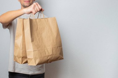Teslimat Konsepti - yakışıklı beyaz teslimatçı marketten bir paket yiyecek ve içecek getirdi. Grey Stüdyo Arkaplanı 'nda izole edilmiş. Boşluğu Kopyala.