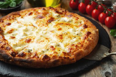 A slice of hot Italian pizza with stretching cheese. Pizza four cheeses with basil on a wooden background.