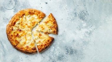 Italian pizza four cheeses with stretching cheese and basil on a light concrete background. Top view with copy space.