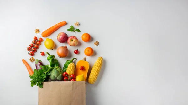Delivery healthy food background. Healthy vegan vegetarian food in paper bag vegetables and fruits on white, copy space, banner. Shopping food supermarket and clean vegan eating concept.