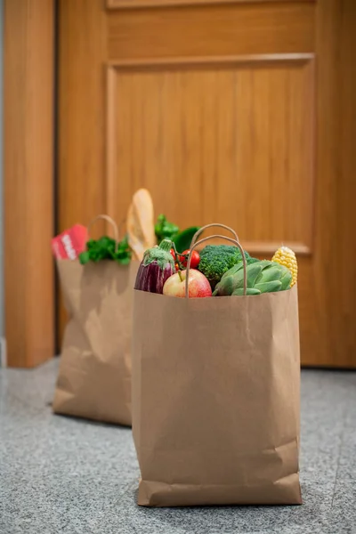 Food shopping bags stand at the door of the house or apartment. Vegetables and fruits delivery during quarantine and self-isolation