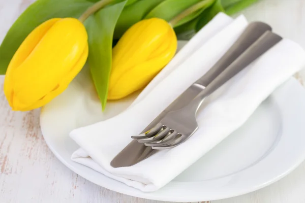 Tallrik med gaffel, kniv, servett och gula tulpaner — Stockfoto