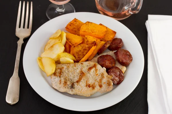 Жареная свинина с чорико, тыквой и яблоком на тарелке — стоковое фото