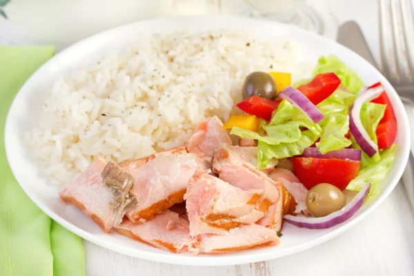 Ryba z ryżem i sałatką na białym talerzu — Zdjęcie stockowe