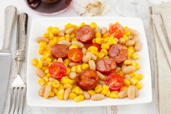 Белая фасоль с кукурузой и жареными колбасами на тарелке — стоковое фото