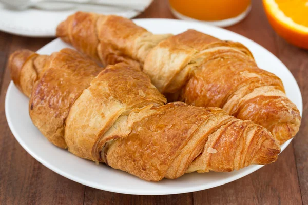 Croissant auf dem Teller mit Saft und Orange — Stockfoto