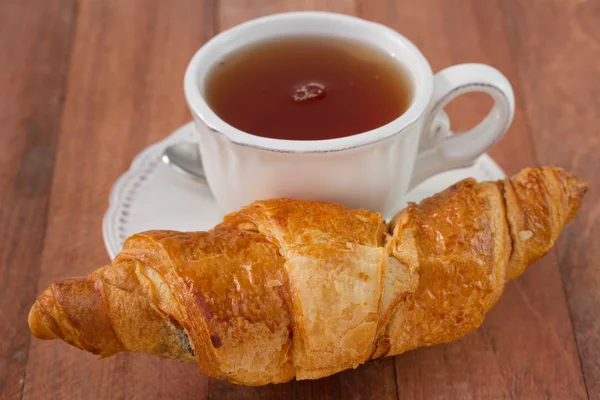 Croissant mit einer Tasse Tee — Stockfoto