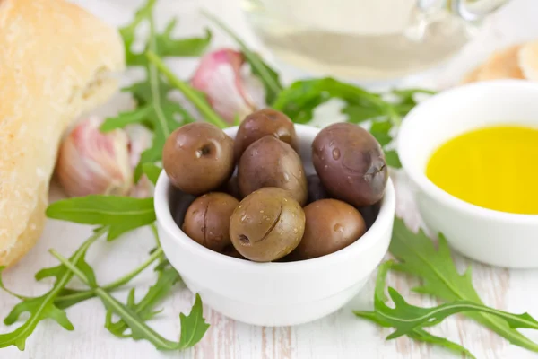 Oliven in der Schüssel mit Knoblauch, Brot und Olivenöl — Stockfoto