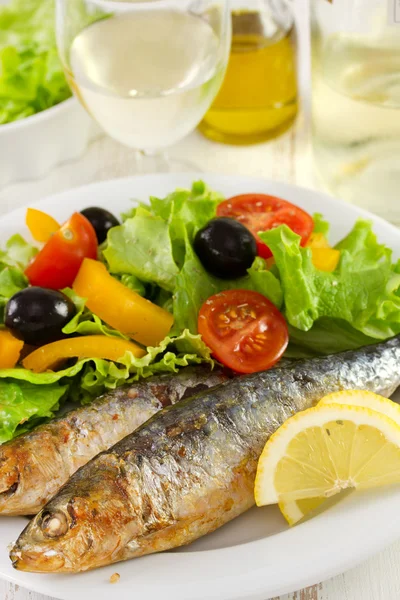 Sardines with lemon and salad on the plate — Stock Photo, Image