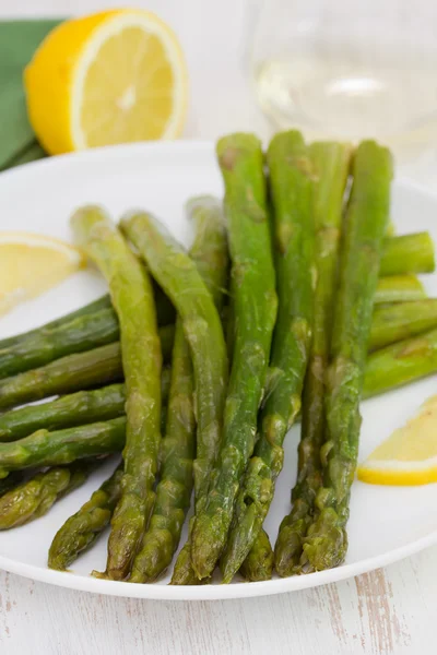 Espárragos con limón en plato blanco —  Fotos de Stock