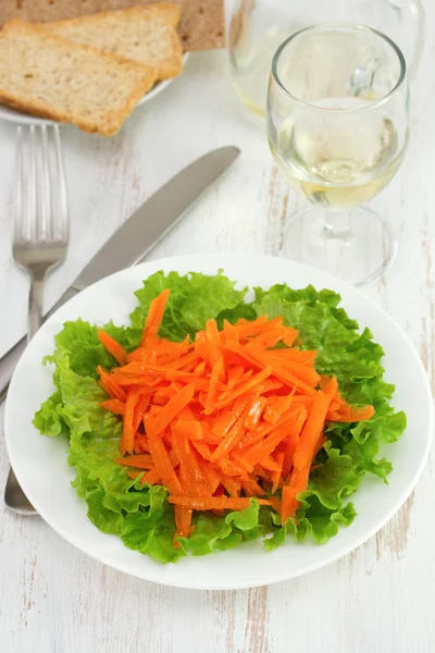 Морковь с салатом на белой тарелке — стоковое фото