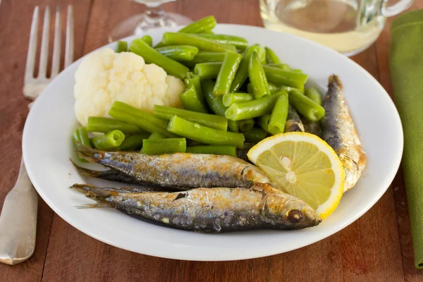 Peixe com legumes no prato branco — Fotografia de Stock