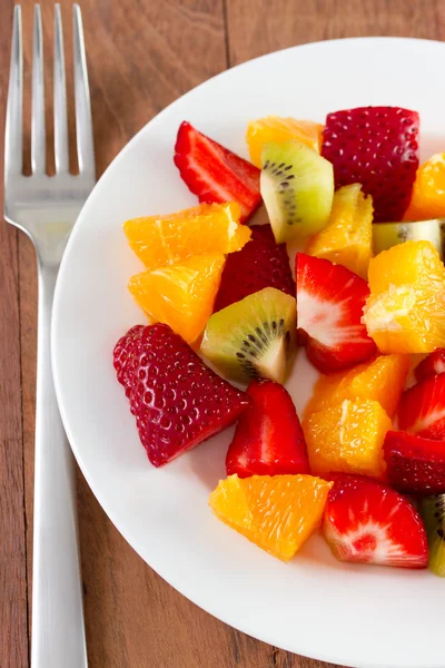 Fruitsalade op wit bord met mes en vork — Stockfoto