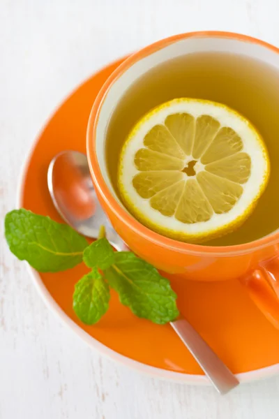 Чай с лимоном в оранжевой чашке — стоковое фото