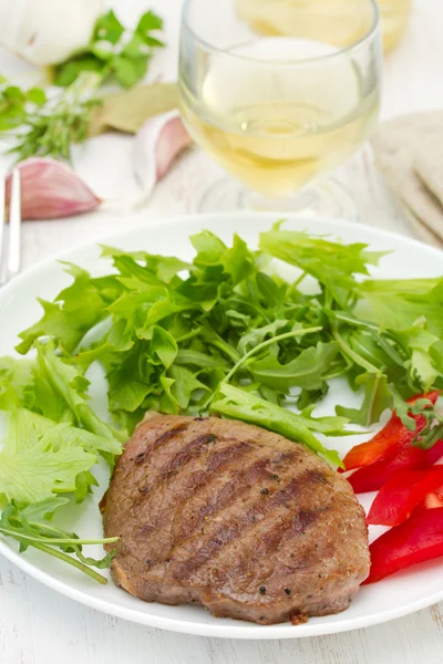 Carne grelhada com alface na placa branca — Fotografia de Stock