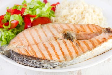 pilav ve salata tabağı üzerinde ızgara somon