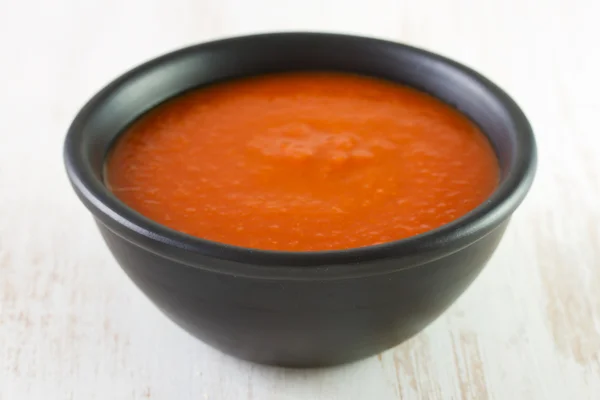 Tomato soup in black dish — Stock Photo, Image