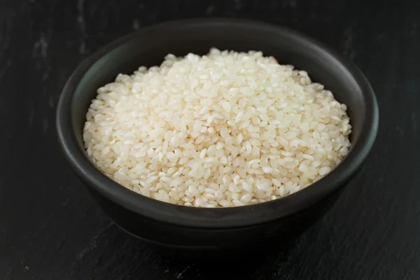 Dry rice in black bowl — Stock Photo, Image