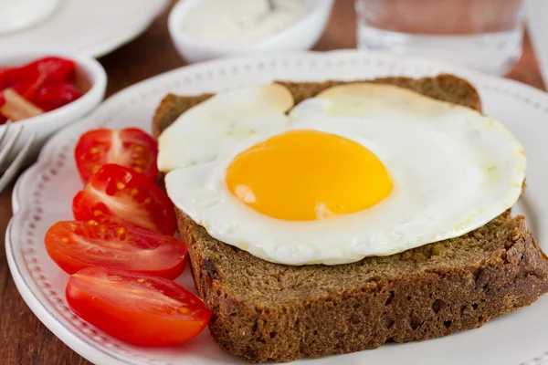 Жареное яйцо с хлебом на белой тарелке — стоковое фото
