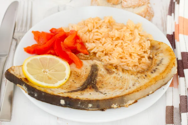 Жареная рыба с вареным рисом на тарелке — стоковое фото