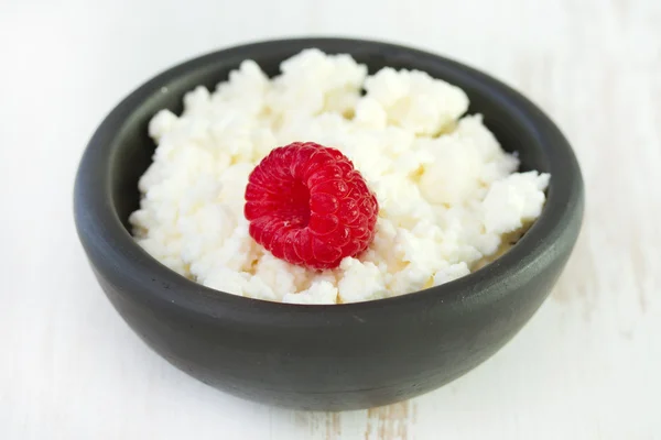 Cottage cheese with raspberry in dark bowl — Stock Photo, Image