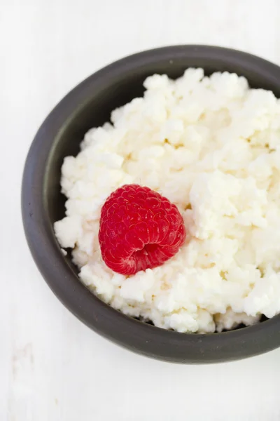 Cottage cheese with raspberry in dark bowl — Stock Photo, Image