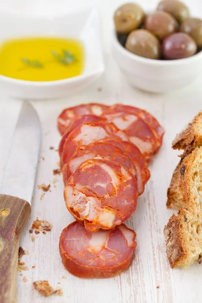 Smoked sausages with olives, bread and oil — Stock Photo, Image