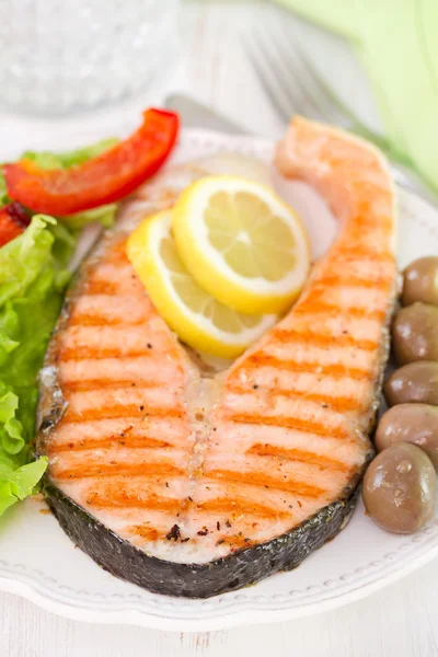 Salmon with lemon, salad and olives — Stock Photo, Image