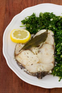 balık haşlanmış lahana beyaz tabakta ve limon ile
