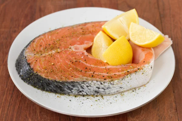 Fresh salmon with lemon on white plate — Stock Photo, Image