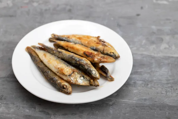 Muitas Pequenas Sardinhas Fritas Placa Branca Mesa Cerâmica Cinza — Fotografia de Stock