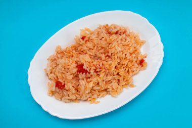 Domatesli haşlanmış pirinç ve mavi arka planda beyaz tabakta baharat.