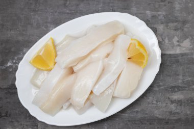 Biberli çiğ kalamar ve seramik zemin üzerinde taze limon.