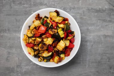 Izgara kabak, biber ve domates seramik üzerinde küçük beyaz kase