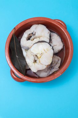 Kahverengi seramik tencerede kaynamış taze balık.