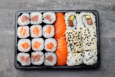 Japon yemekleri gri seramik üzerinde siyah plastik kutuda.