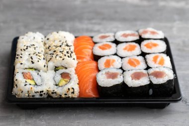 Japon yemekleri gri seramik üzerinde siyah plastik kutuda.