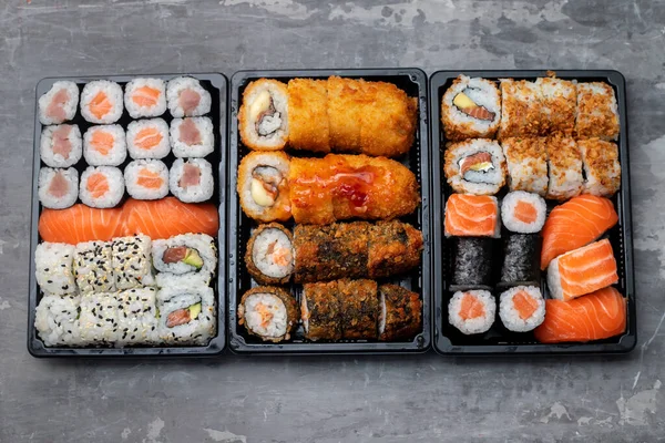 Japon yemekleri gri seramik üzerinde siyah plastik kutuda.