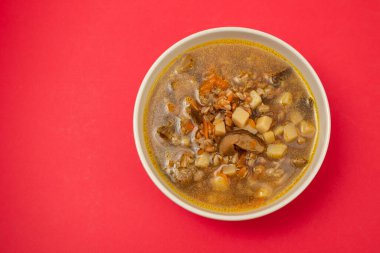 Taze mantar çorbası küçük kahverengi kâse içinde kırmızı kağıt üzerinde