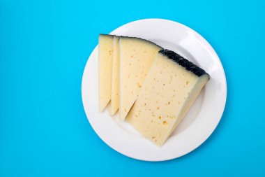 slices cheese on white small plate on blue