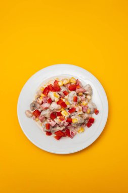 Beyaz tabakta soslu fasulye, mısır ve kırmızı biber.