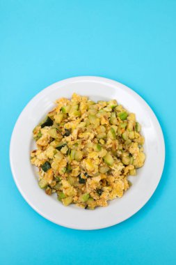 Çırpılmış yumurta ve kabak. Mavi kağıtta beyaz küçük tabak.