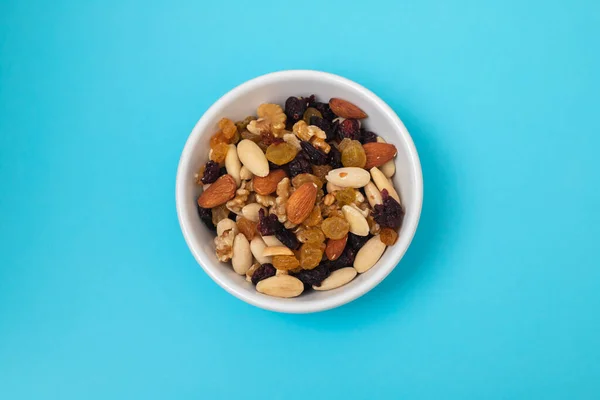 mix dry fruits in white small bowl on blue paper