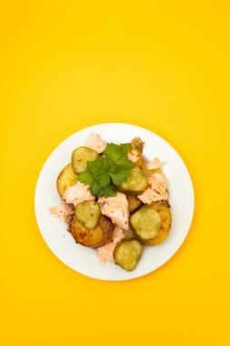 Kızarmış patatesli taze somon balığı ve beyaz tabakta salatalık.