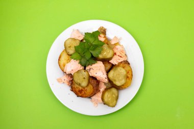 Kızarmış patatesli taze somon balığı ve beyaz tabakta salatalık.