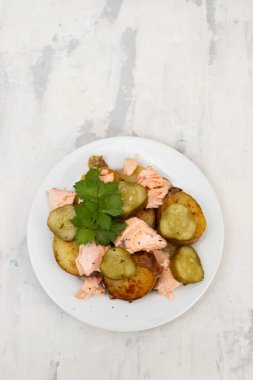 Kızarmış patatesli taze somon balığı ve beyaz tabakta salatalık.