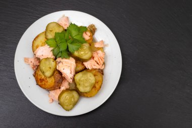 Kızarmış patatesli taze somon balığı ve beyaz tabakta salatalık.