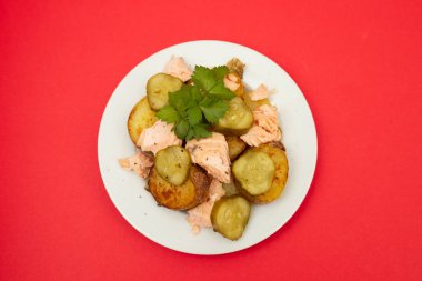 Kızarmış patatesli taze somon balığı ve beyaz tabakta salatalık.