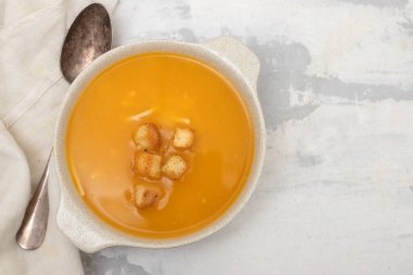 Gri seramik üzerinde beyaz kasede kraker bulunan sebze çorbası.