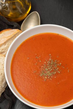 fresh cold tomato soup with herbs in the bowl on ceramic